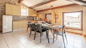 A kitchen with a dining table, chairs, and a refrigerator. - Apartment “Maison d’Odette” with Lagoon View, Wi-Fi, and Air Conditioning (Gruissan)