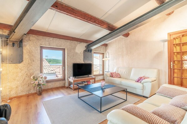 A living room with a television, sofa, coffee table, and a view of the outdoors.