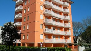 Un edificio residencial de varios pisos con balcones, una señal de no estacionamiento y un cielo azul despejado.