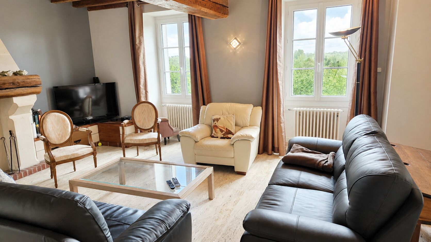 Een woonkamer met een bank, fauteuil en een glazen salontafel.