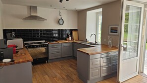 A modern kitchen with a gas stove, a sink, and a large window. - Country house, privacy and nature. (Lesges)
