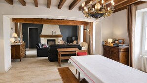 Una habitación con cama, un banco de madera, un sofá, una chimenea y una televisión.