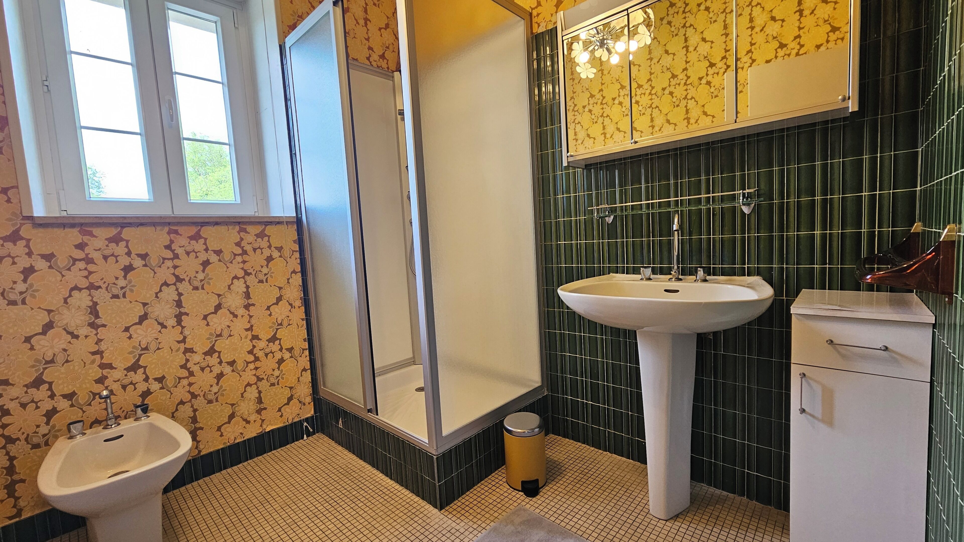 A bathroom with a toilet, bidet, sink, and shower.