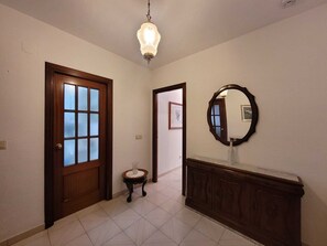 A hallway with a wooden door, a small table with a glass, and a mirror on the wall. - Tradicional Casa amplia y luminosa con una ubicación excepcional en Ronda (Ronda)