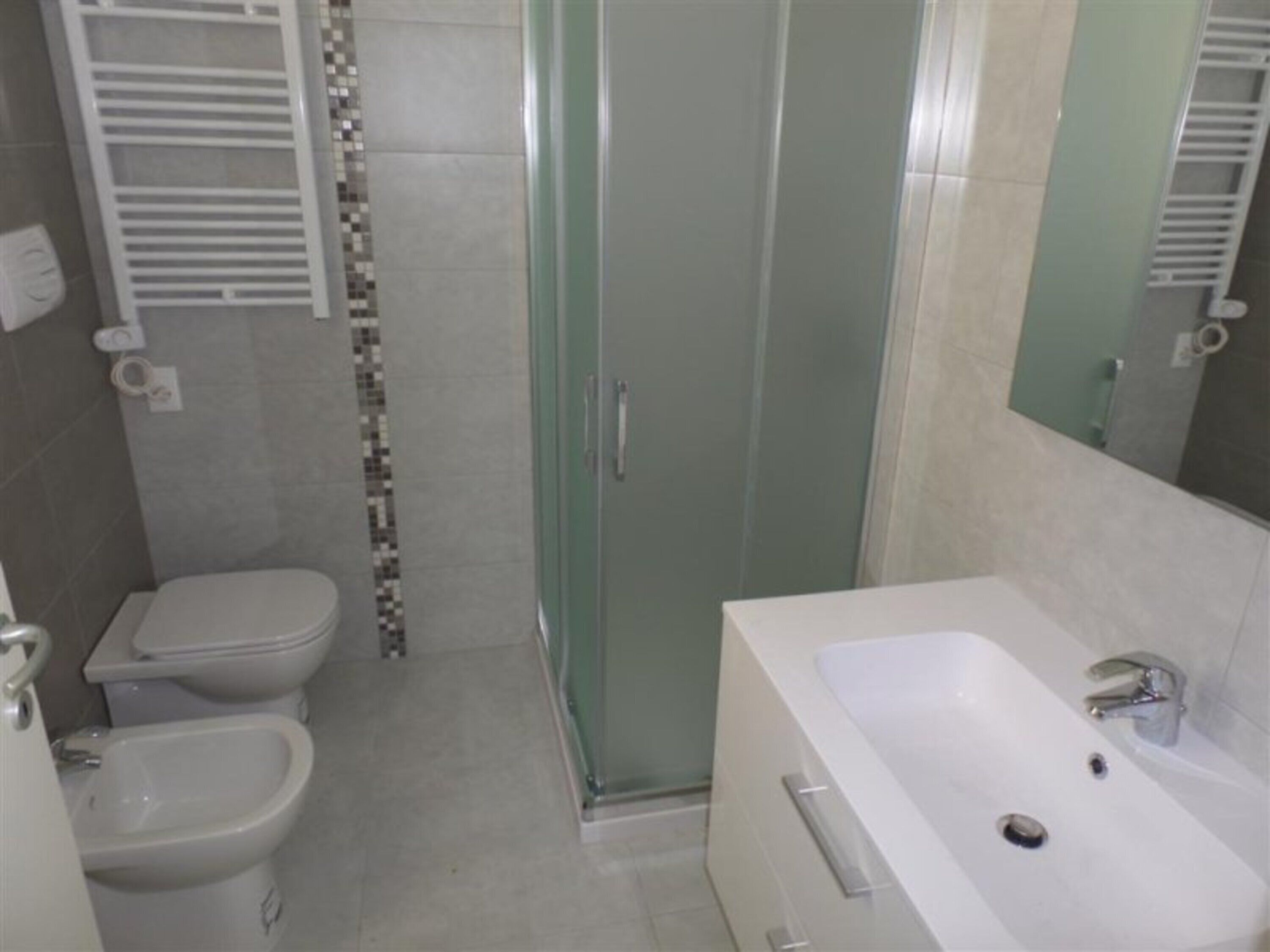 Baño con inodoro, bidé, ducha y lavamanos.