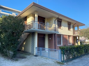 Ein zweistöckiges Gebäude mit Balkon, Treppe und einem geschlossenem Eingang.