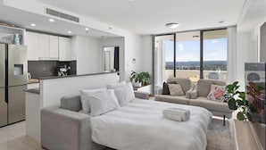 Un apartamento moderno con kitchenette, una cama grande, un sofá y un balcón con vista a la ciudad.