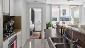 Una cocina moderna con estufa, lavaplatos y vistas a la ciudad a través de amplios ventanales.