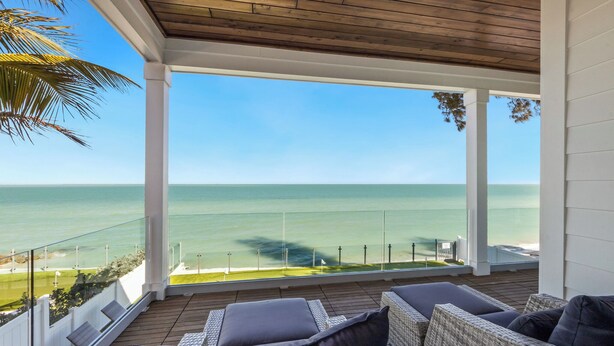 Ein überdachter Balkon mit Korbmöbeln und Blick auf das Meer.