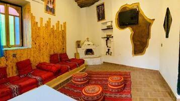 Une pièce avec un mur en bois, un canapé, une cheminée, un téléviseur et un tapis à motifs.