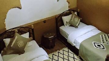 Ein Zimmer mit zwei Betten, einem gemusterten Teppich und einem dekorativen Wandvorhang.