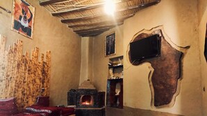 Un salon chaleureux avec une cheminée, un canapé et un téléviseur fixé au mur.