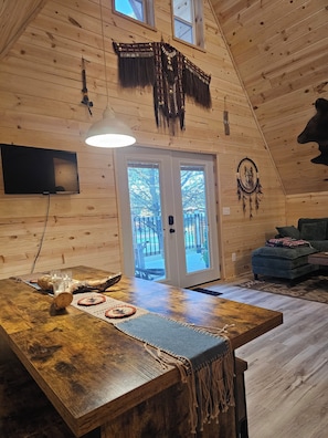 A wooden interior with a large table, a TV, and a dreamcatcher.
