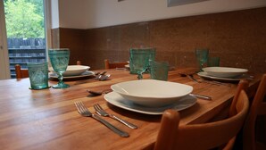 Una mesa de comedor preparada con platos, tazones y cubiertos, rodeada de sillas.