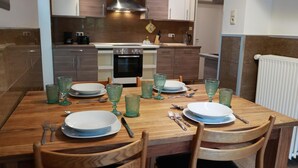 Un comedor con una mesa de madera dispuesta para cuatro personas, con platos, vasos y cubiertos.