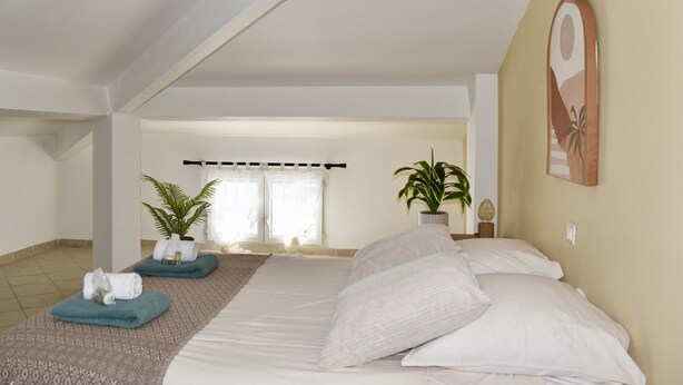 A bedroom with a large bed, two potted plants, a painting, and a view of a balcony. - Seafront Palatino Apartment for 8 (Martigues)