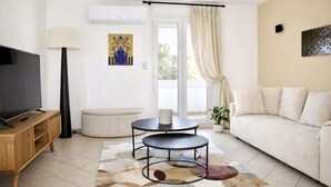 A living room with a TV, sofa, two tables, a lamp, and a potted plant. - Seafront Palatino Apartment for 8 (Martigues)