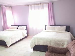 A bedroom with two beds, each with a white fluffy bedspread and dark headboards.