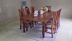 Un tavolo da pranzo con sei sedie di legno, un distributore d'acqua e un vaso con fiori sul tavolo.