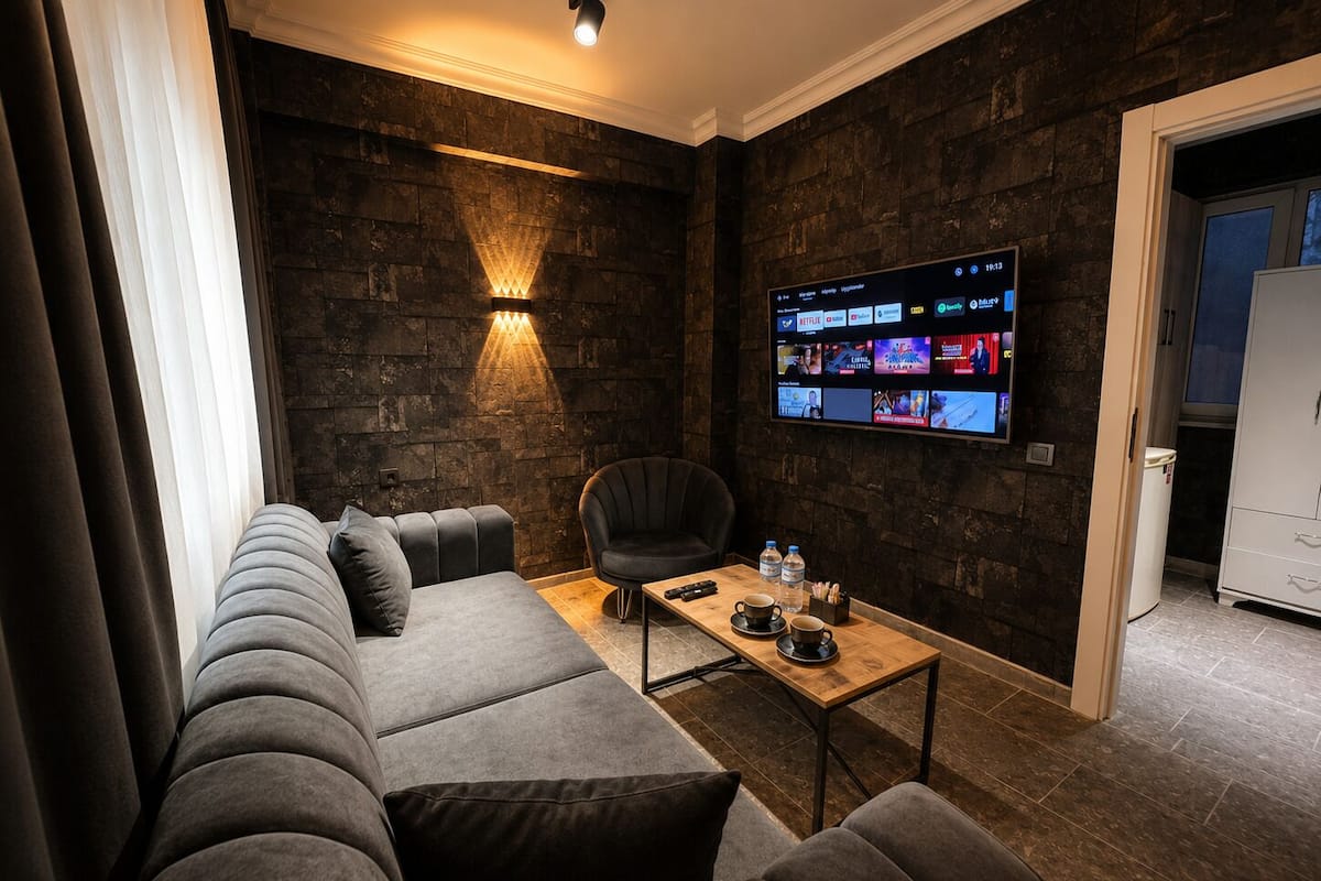 Una sala de estar moderna con una pared de piedra, un televisor de pantalla plana grande, un sofá y una mesa de centro.
