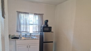 A compact kitchen with a refrigerator, microwave, sink, and window with curtains. - Nice renovated 1 bedroom Apartment Sunny Days Motel 3 (St. Petersburg)