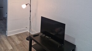 A room with a TV on a stand, a floor lamp, and a painting on the wall. - Nice renovated 1 bedroom Apartment Sunny Days Motel 3 (St. Petersburg)