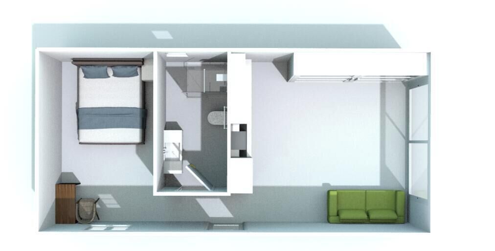 A room with a bed, a small kitchenette, a green sofa, and a bathroom.