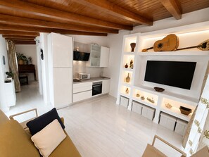 A modern kitchen with white cabinets, a built-in microwave, and a TV mounted on the wall. - Mimosetta Guest House: A Cozy Cottage Surrounded by Peace and Greenery, with Views of the Sea and Mountains (Vallebona)