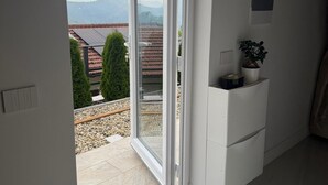 Une pièce dotée d’une porte-fenêtre coulissante donnant sur un balcon, d’une petite armoire blanche et d’une plante en pot.