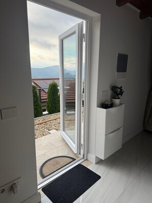 A room with a sliding glass door leading to a balcony, a small white cabinet, and a potted plant. - Mimosetta Guest House: A Cozy Cottage Surrounded by Peace and Greenery, with Views of the Sea and Mountains (Vallebona)