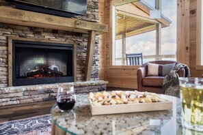 Ein gemütliches Wohnzimmer mit Kamin aus Stein, einer bequemen Ledersofa und einem Glastisch mit Snacks und einem Glas Wein.