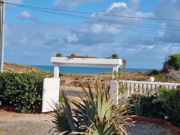 A coastal property with a white pergola, a gravel pathway, and a view of the sea. - 1 bedroom seaside apartment (El Jadida)
