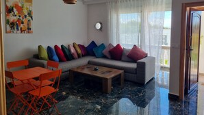 Ein modernes Wohnzimmer mit einer Eckcouch, einem Couchtisch aus Holz und orangefarbenen Sesseln.