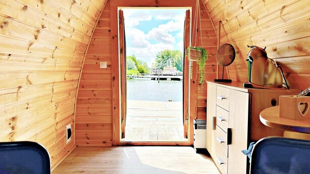 A wooden cabin interior with a view of a dock and water outside. - Unique Water Bubble by the Marina (Almere)