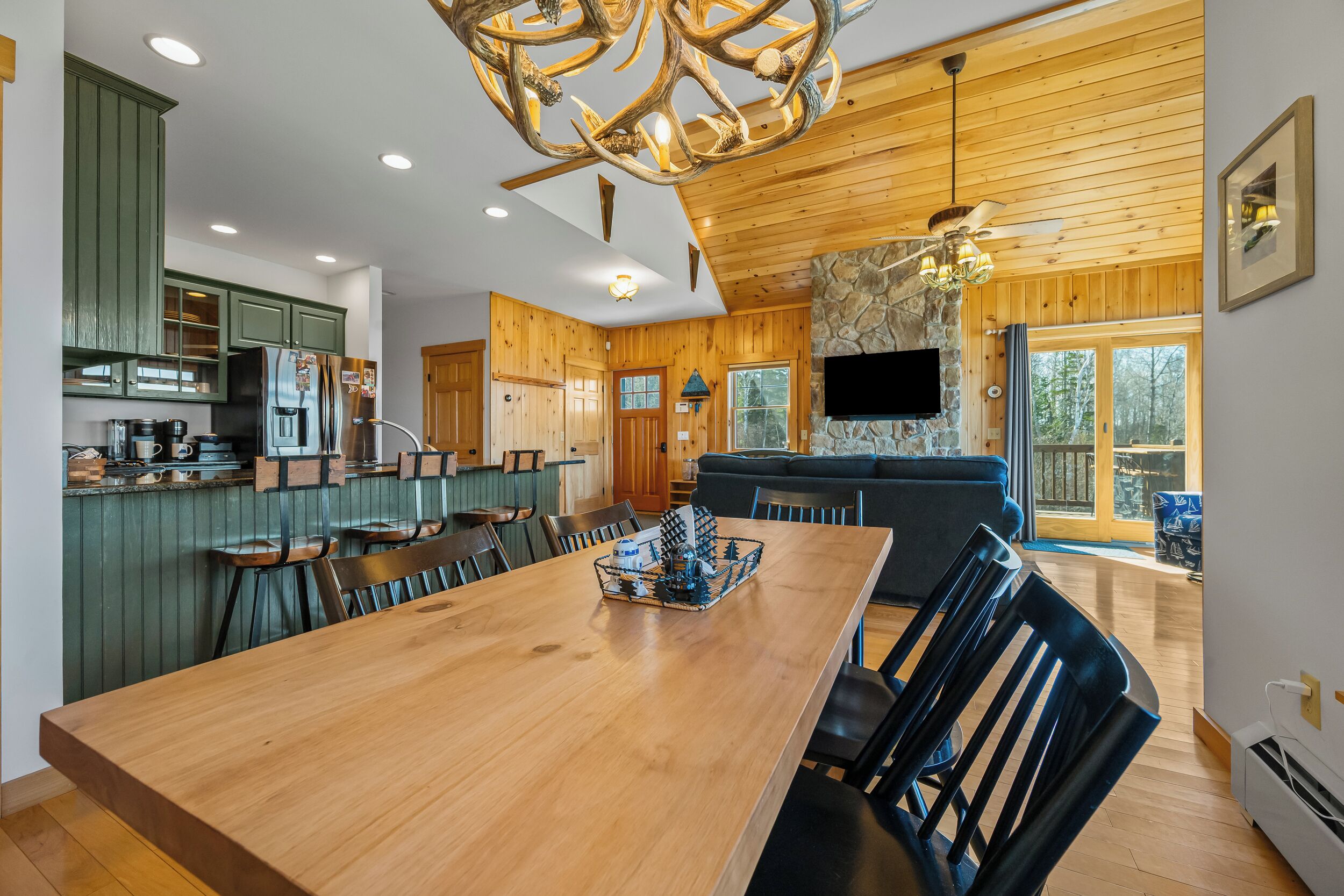 A spacious kitchen with wooden cabinets, a dining table, and a large chandelier.