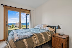 Ein Schlafzimmer mit Bett, Nachttisch und Blick ins Freie.