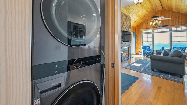 A modern kitchen with a built-in washer and dryer, wooden ceiling, and a view of the outdoors. - Lodges 12 | Lake Views | Modern Condo (Rangeley)