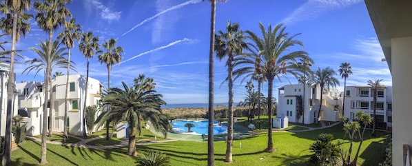 A resort with a pool, palm trees, and ocean views. - Deltamar 81, Solo Familias! (Playa Xeraco)