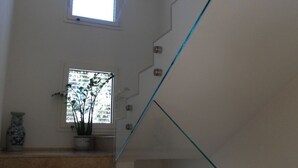 A staircase with glass railings and a potted plant on the landing. - Villa Celeste Flexrent - Abissinia Real Estate (Scacciano)