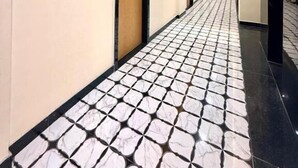 Un pasillo de hotel con suelo de baldosas, cuadros en las paredes y puertas.