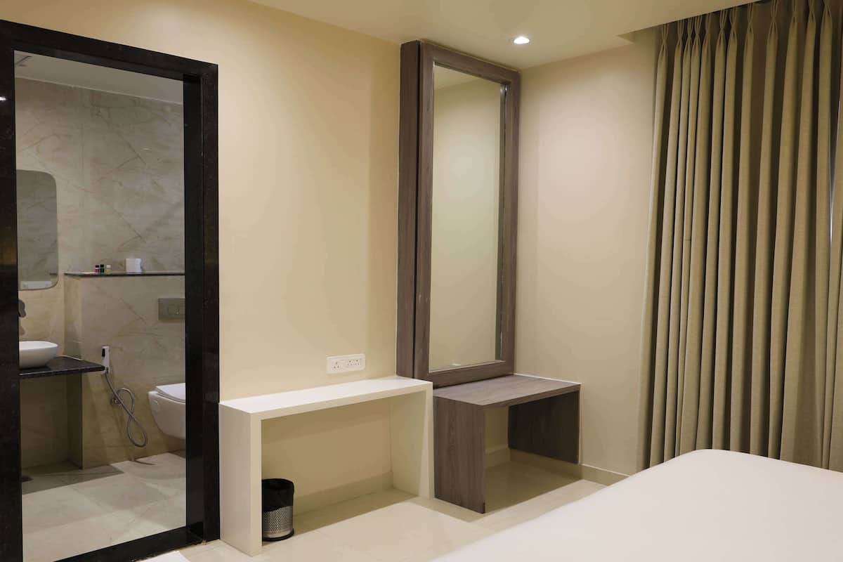 A modern bathroom with a large mirror, a toilet, a sink, and a shower area.