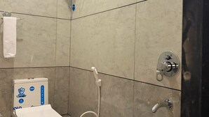 Baño con inodoro, un cubo azul y calentador de agua.