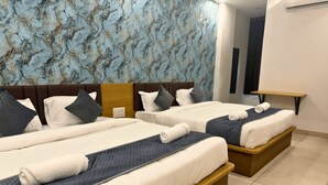 Habitación de hotel con dos camas, pared con diseño de mármol, cabecero de madera y una mesita.