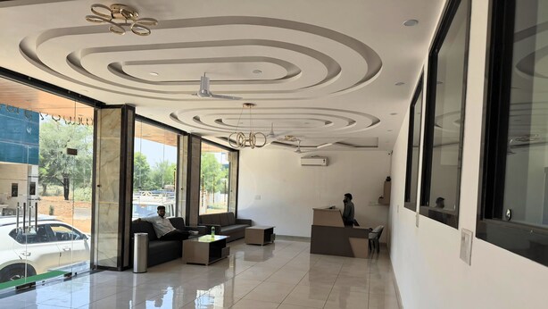 Un moderno vestíbulo de hotel con mostrador de recepción, zona de estar y ventanas amplias que ofrecen vistas al exterior.