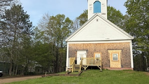 A small, single-story building with a white exterior and a blue window at the top. - Welcome to "the east Madison chapel" (Madison)