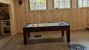 A wooden-floored room with a foosball table, windows, and a shelf with items. - Welcome to "the east Madison chapel" (Madison)