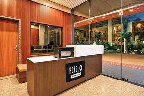 A hotel reception desk with a wooden finish and a sign indicating it is serviced by OYO. - Classic Super Hotel O Khatu Shyam Temple (Danta Ramgarh)