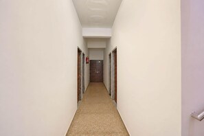 A narrow hallway with a fire extinguisher on the wall, a door at the end, and a carpeted floor. - Classic Super Hotel O Khatu Shyam Temple (Danta Ramgarh)