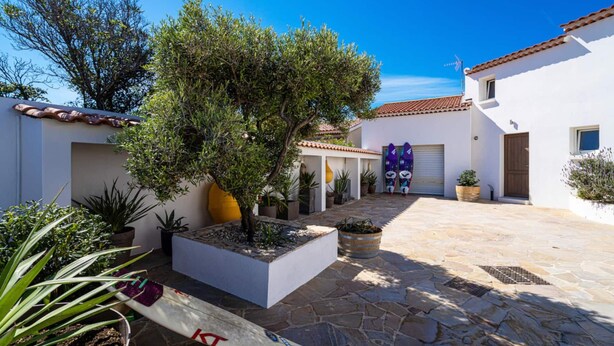 A courtyard with a tiled floor, potted plants, and a surfboard. - Carro Beach House Villa D'exception Vue Mer (Martigues)