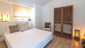 A bedroom with a large bed, a chair, a wooden partition, and a wall-mounted lamp. - Carro Beach House Villa D'exception Vue Mer (Martigues)